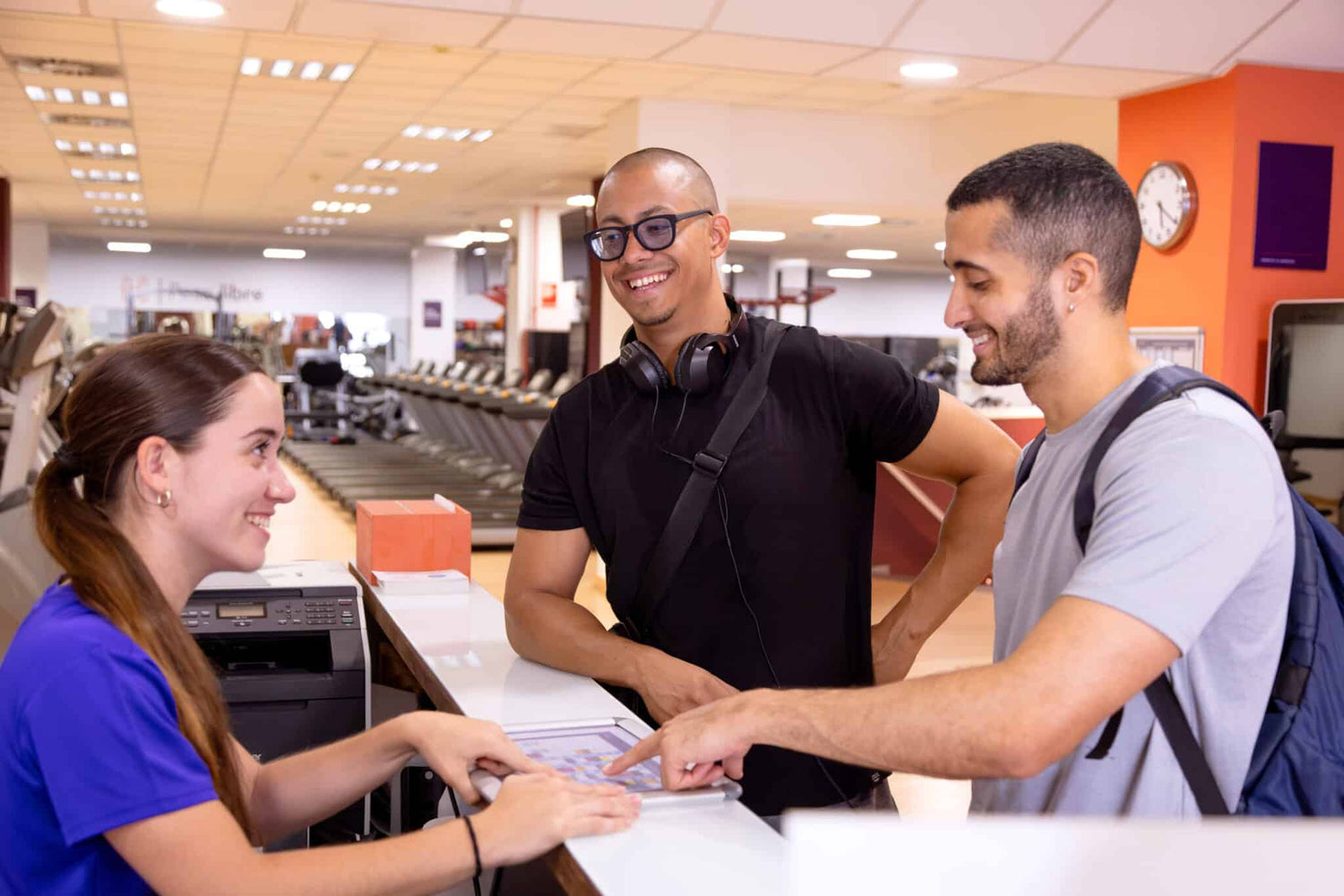 Receptionist attending two sportive men in a gym