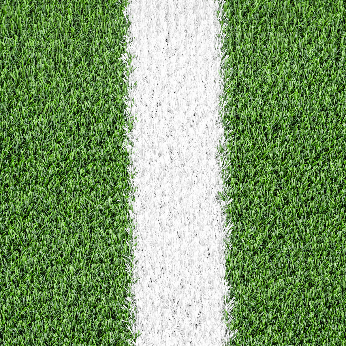 Pormenor dos filamentos verdes e da linha branca da relva artificial GRASS para pistas de treino funcional.