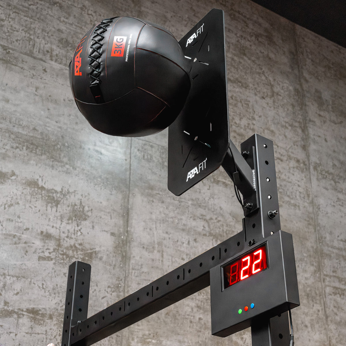 Bola de wall ball junto ao alvo WALLCOUNT AZAFIT durante o treino, com contador LED vermelho por baixo.